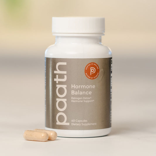 Supplement bottle labeled 'paath Hormone Balance' with two capsules on a neutral background