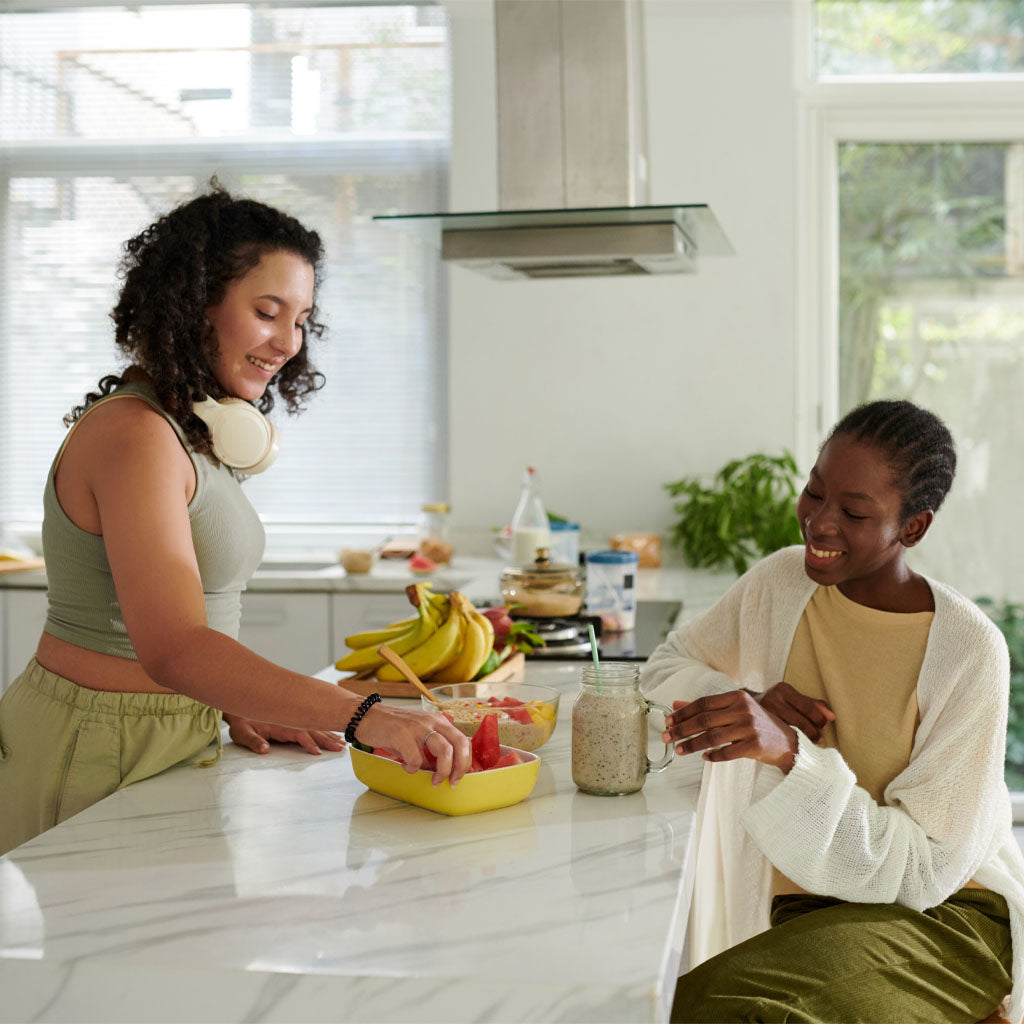 Two women in a kitchen preparing food together.
